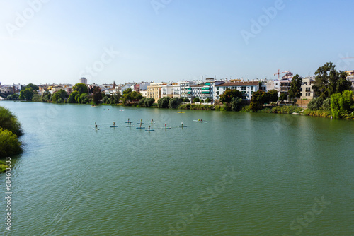 An instructor teaches paddle surfing to a group of children on the Guadalquivir river in Seville, Spain.
