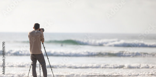 Young handsome photographer with a tripod and a camera on the beach photo