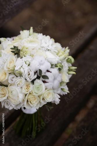 Wedding bouquet with white flowers on a wooden stairs. Bouquet with ranunculus  lisianthus  freesia and cotton flowers.