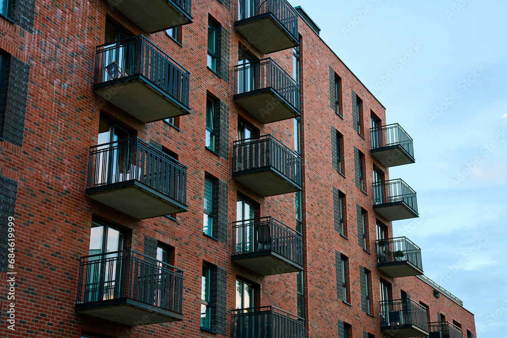 Residential building facade with balconies and windows. Modern city architecture. Apartment building made of red bricks