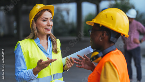 Professional constructors check a building. Architects walking inside a building, close up. Two workers talking at a construction site, standing in a building in the framing stage.