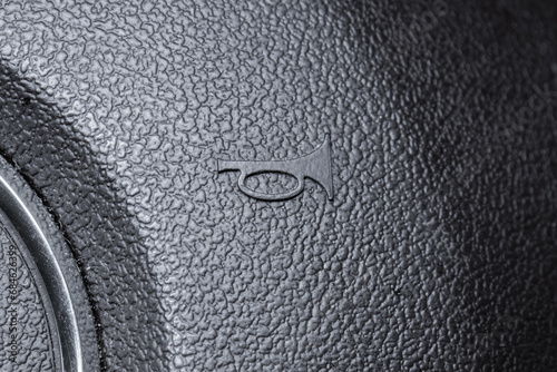 Modern car air horn icon or symbol on a steering wheel. Close up macro shot, no people photo