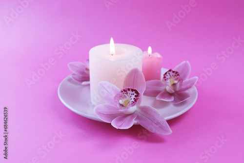 Fresh pink orchid flowers, burning candles, sea salt, on a bright pink background, spa concept, relaxation atmosphere, body care 