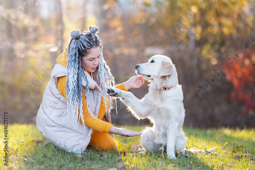 a girl with dreadlocks is asking to give her dog a paw
