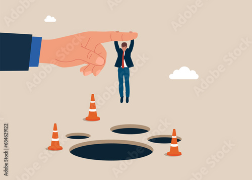 Solve business problem. Businessman hangs on for dear life from a behind the big finger hand as he swings above a pits and obstacle. Flat vector illustration