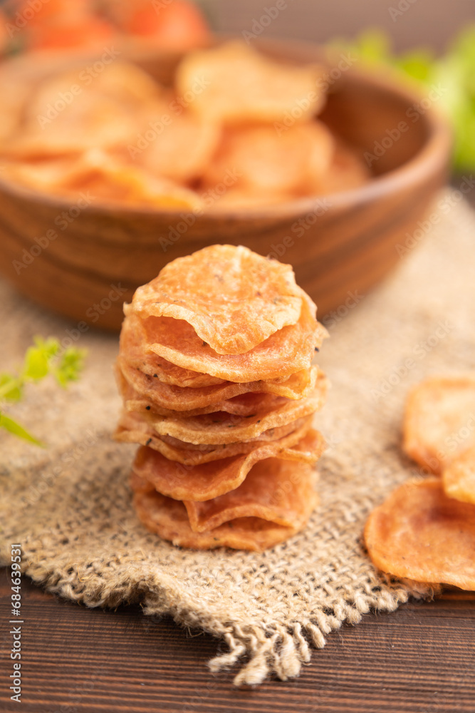 Slices of dehydrated salted meat chips on brown wooden, side view, selective focus