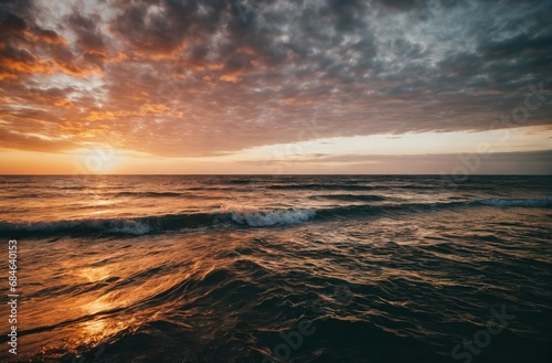 Sunset horizon over ocean with waves and cloudy sky. 