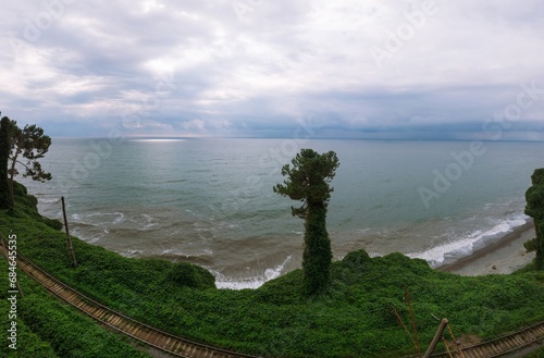 Wide aerial panoramic view Railway Station and Black Sea coast flora with calm seashore in summer. Rain clouds, storm. Tsikhisdziri Georgia. The railway photo