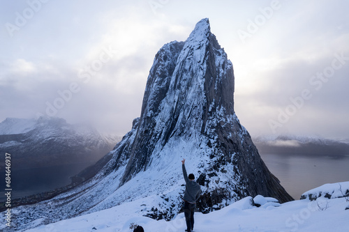 Hiker climbing snowy mountain hike up Segla in Senja, Norway. A man walking up snowcapped mountains in the Arctic Circle of Northern Norway. Famous hike on Senja island. Shot in October