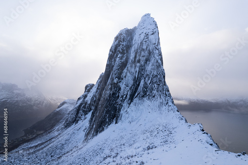 Aerial drone photo of snowy mountain hike up Segla in Senja, Norway. Snowcapped mountains in the Arctic Circle of Northern Norway. Famous hike on Senja island. Shot in October.