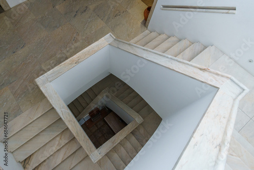 Rectangular spiral stairway made out of white marble