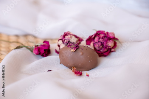 Chocolate pieces with flowers and roses on pink and white background also with mock up space