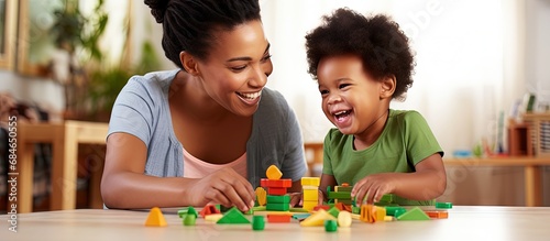 An African child plays with educational toys while supported by his mother and kindergarten teacher copy space image