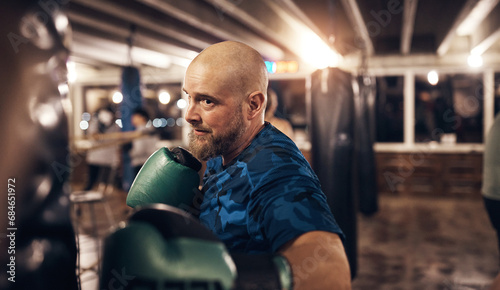Mature man hitting a punching bag in a boxing gym photo