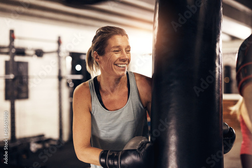 Mature woman laughing while exercising with a boxing gym punching bag photo