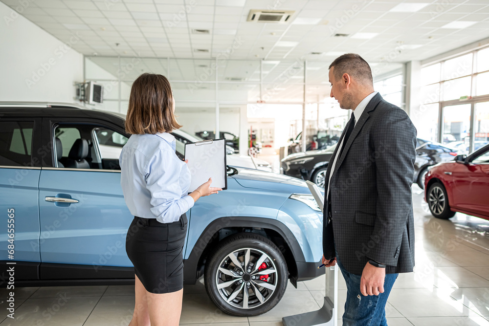 Seller with clipboard and buyer talking about purchase new car in the showroom Seller with clipboard and buyer talking about purchase new car in the showroom