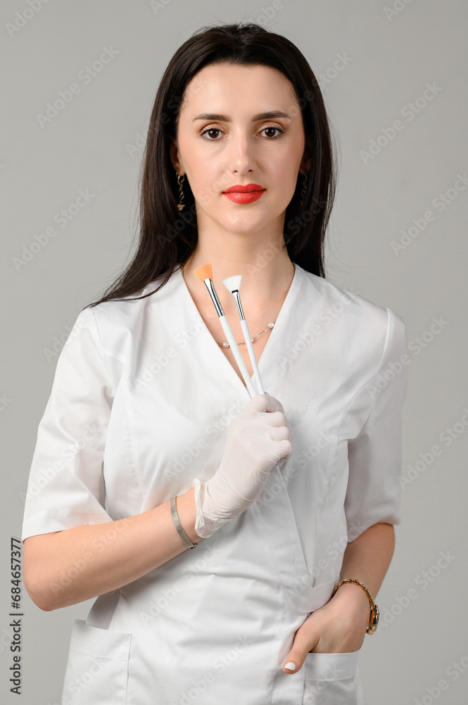 the girl cosmetologist holds two brushes in her hands on a white background the girl cosmetologist holds two brushes in her hands on a white background