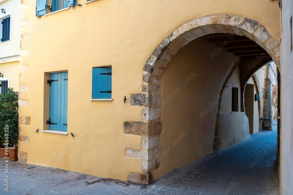 Crete island, Chania Old Town, Greece. Building over arched stonewall that covers paved alley.