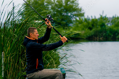 Obraz na plátne Fisherman casts a fishing rod or spinning rod into the water while sitting on th