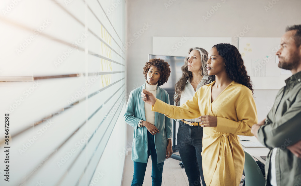 Diverse businesspeople having a brainstorming session with adhesive notes in an office Diverse businesspeople having a brainstorming session with adhesive notes in an office