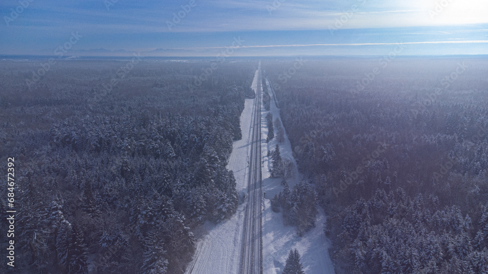 Fototapeta premium Top view of train track rails crossing through snowy forest in winter near Munich