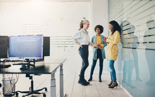Three diverse businesswomen laughing together in an office