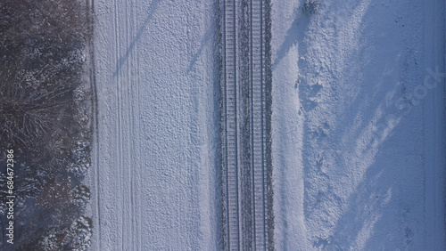 Top view of train track rails crossing through snowy forest in winter near Munich photo