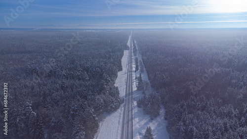 Top view of train track rails crossing through snowy forest in winter near Munich