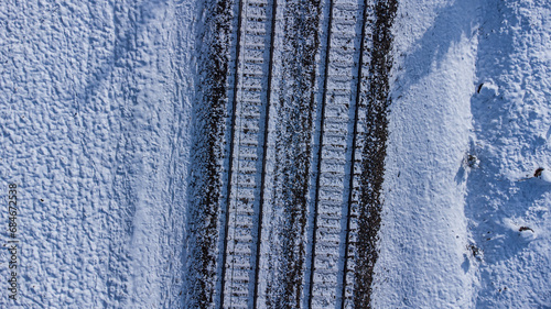 Top view of train track rails crossing through snowy forest in winter near Munich photo