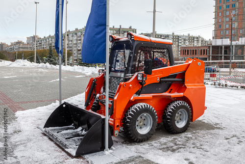 Skid-steer loader in a parking lot in the city on a winter day photo