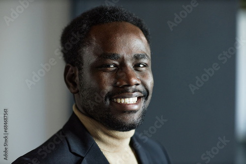 Close up shot of young Black man in suit with beaming smile looking at camera