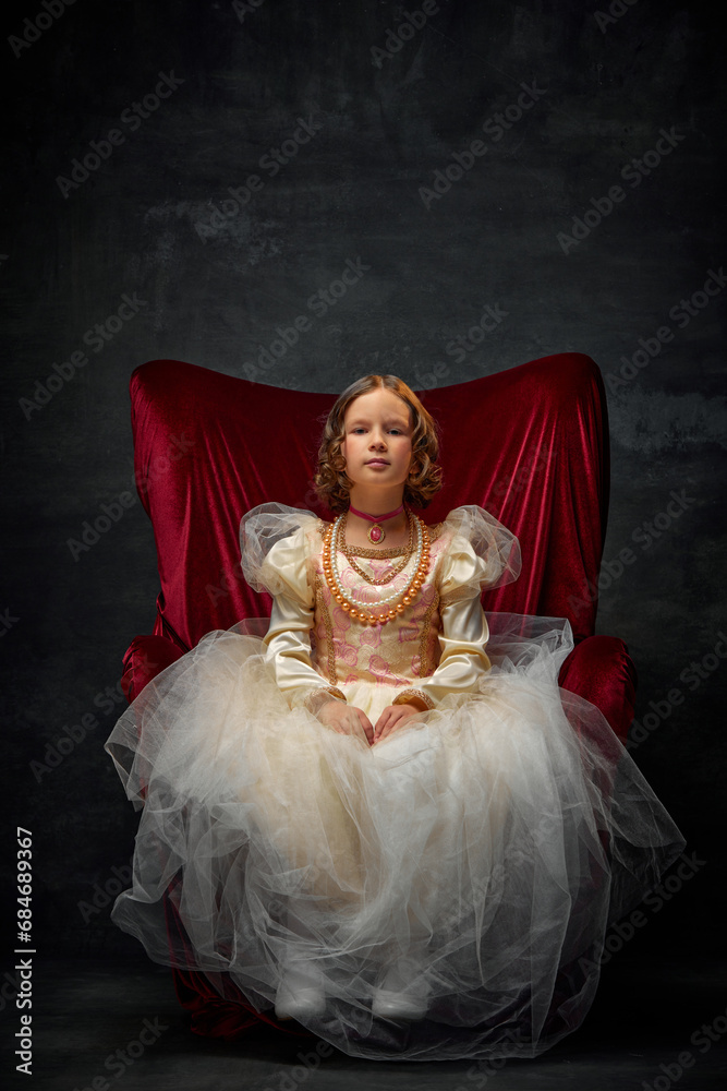 Fototapeta premium Portrait of little girl, kid dressed like medieval person in old-fashioned dress sitting on throne against dark vintage background.