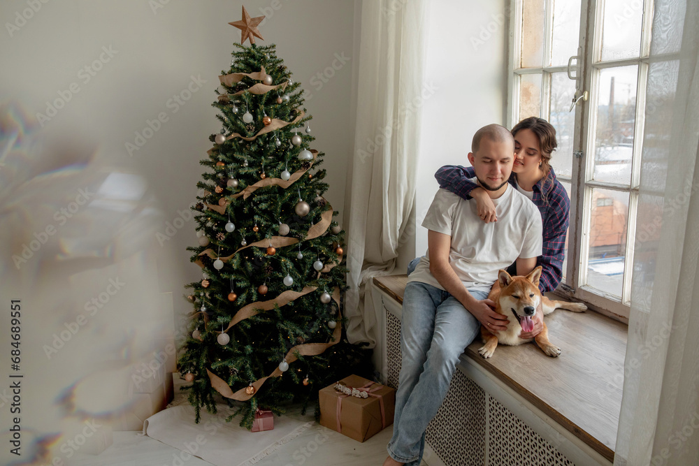 Happy beautiful couple with shiba inu dog at christmas at home Happy beautiful couple with shiba inu dog at christmas at home