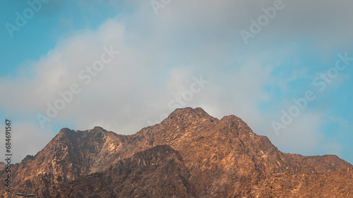Fujairah mountains  extension of Omani Al Hajar mountain range. Cloudy winter day on empty street.