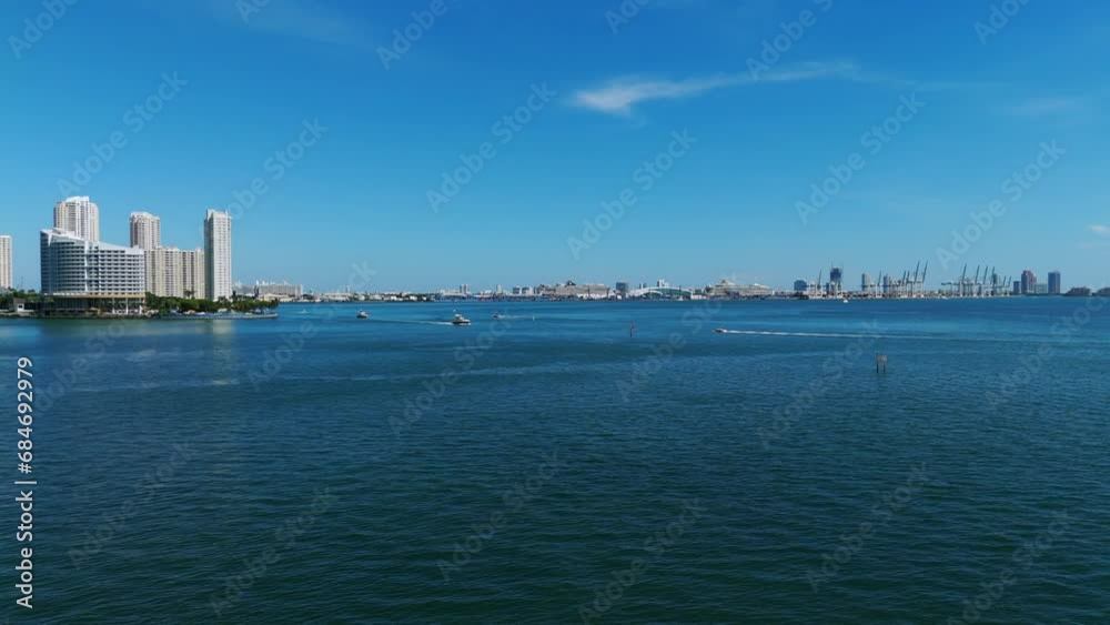 Drone view of sailboats moving in water with Miami urban scenery on background. Blue surface of southern ocean and beautiful skyscrapers in distance Drone view of sailboats moving in water with Miami urban scenery on background. Blue surface of southern ocean and beautiful skyscrapers in distance