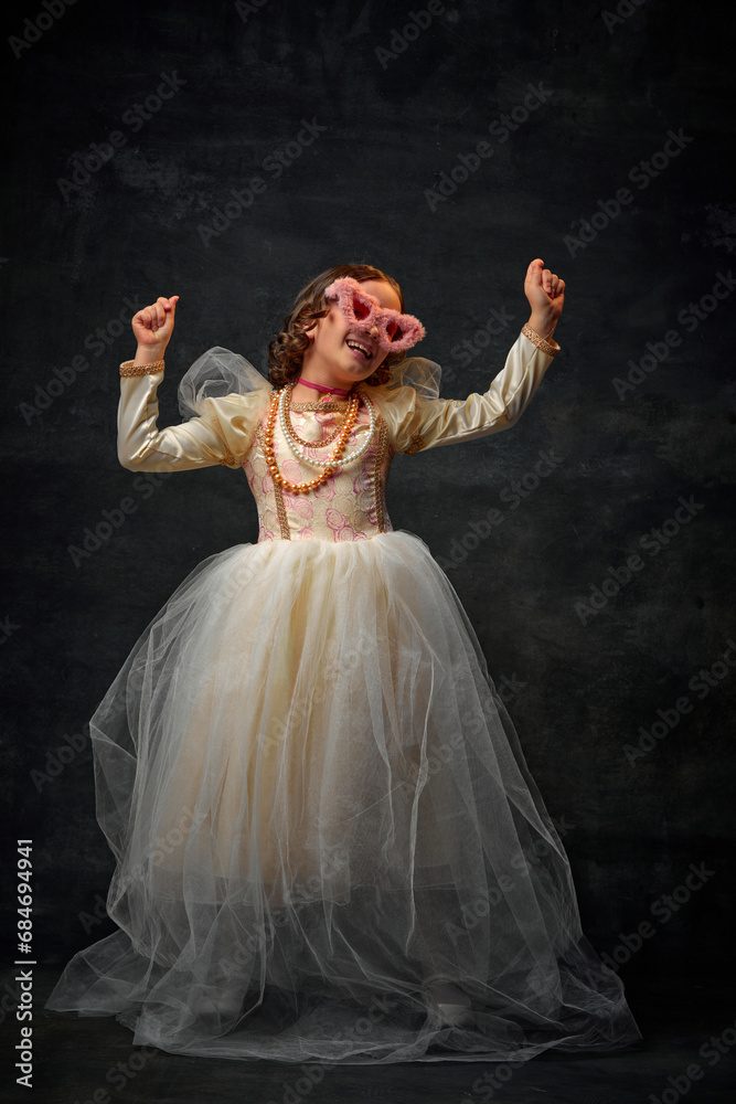 One little royal person, small girl dressed in old-fashioned costume with modern accessories an dancing against vintage background. One little royal person, small girl dressed in old-fashioned costume with modern accessories an dancing against vintage background.