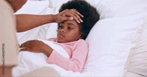 Mother, child and hands on forehead in bed, monitor wellness in family home for cold or flu. Black woman, daughter and check temperature for illness with worry, concern and care for sick kid in house photo
