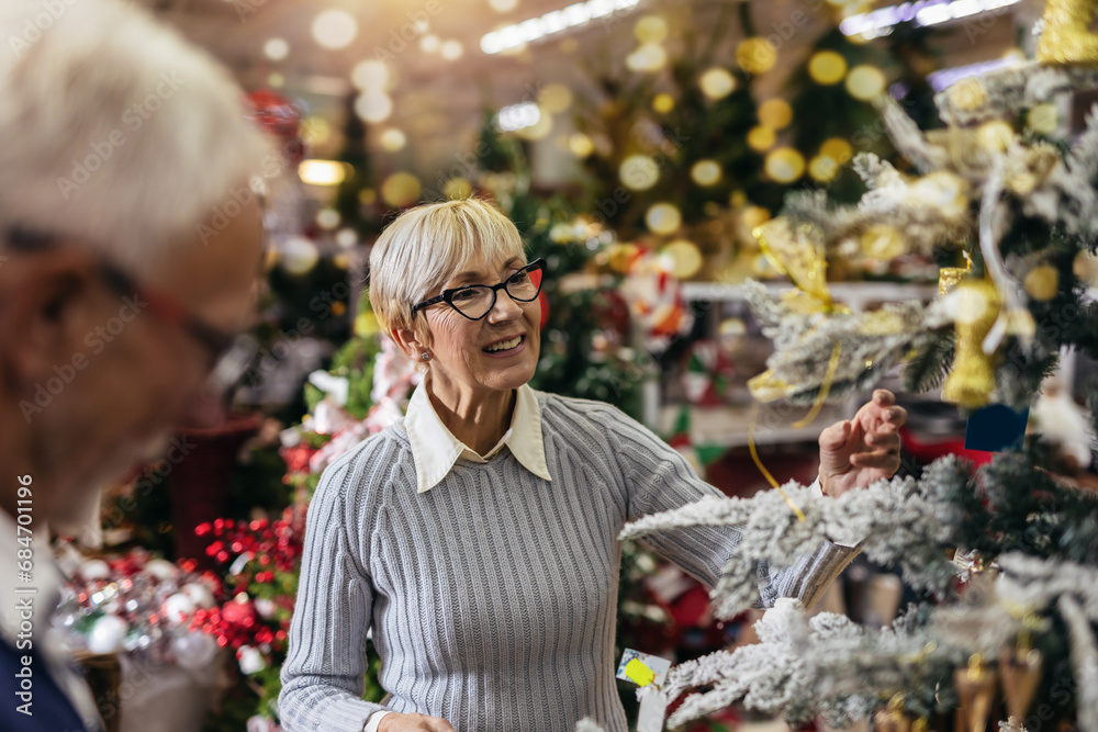 Senior couple at Christmas Market buying decor toys and balls. Concept of Christmas and New Year shopping.