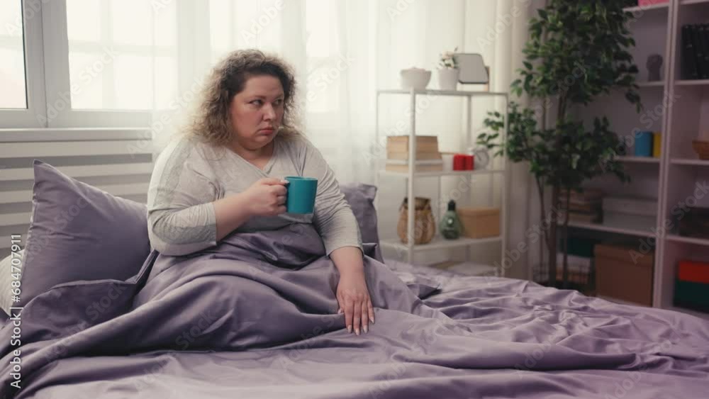 Sleepy overweigh woman drinking coffee in bed, morning headache, chronic fatigue Sleepy overweigh woman drinking coffee in bed, morning headache, chronic fatigue
