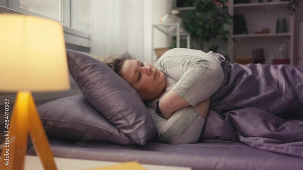 Annoyed overweight woman turning in bed, sleepless night due to noisy neighbors Annoyed overweight woman turning in bed, sleepless night due to noisy neighbors