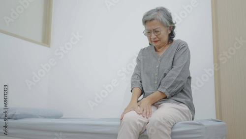 Asian senior elderly woman has problem on joint knee leg and suffer ache health care problem on patient bed, pain in the elderly, Grandmother with knee pain, need walker staff to support help photo