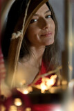 portrait beautiful young brunette woman, looking through a sleigh with fairy lights, smiling, joyful, Christmas spirit