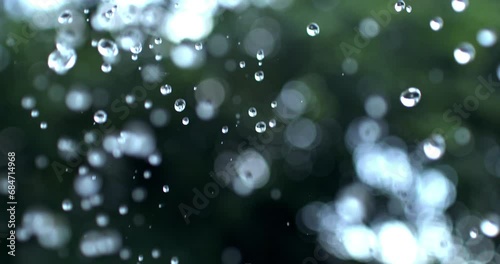 Super slow motion macro of fresh rain water drops are falling down on exotic tropical rainforest plants nature background during raining season. photo