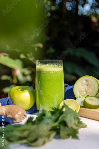 Green smoothie with cucumber, apple and celery on table