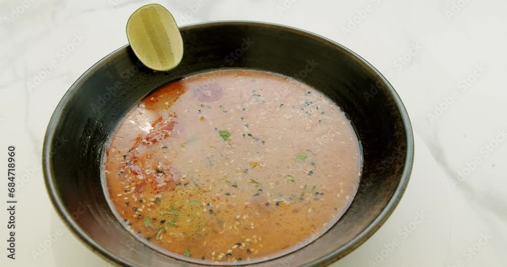Delicious Vegetable Soup Rotating on white background. cream tomato and Vegetable soup with ingredients and lime in black plate on white background. Delicious Vegetable Soup Rotating on white background. cream tomato and Vegetable soup with ingredients and lime in black plate on white background.