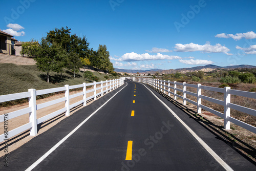 Suburban bike path with white fencing along the San Francisquito Creek Trail in Santa Clarita California.