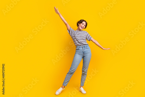 Full body portrait of overjoyed pretty lady raise hands have good mood dance empty space isolated on yellow color background