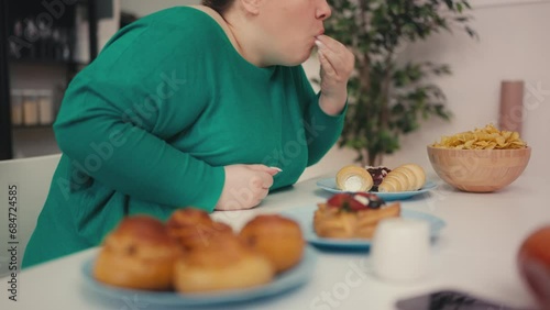 Hungry overweight female overeating salty junk food, sweet cake, stress eating photo