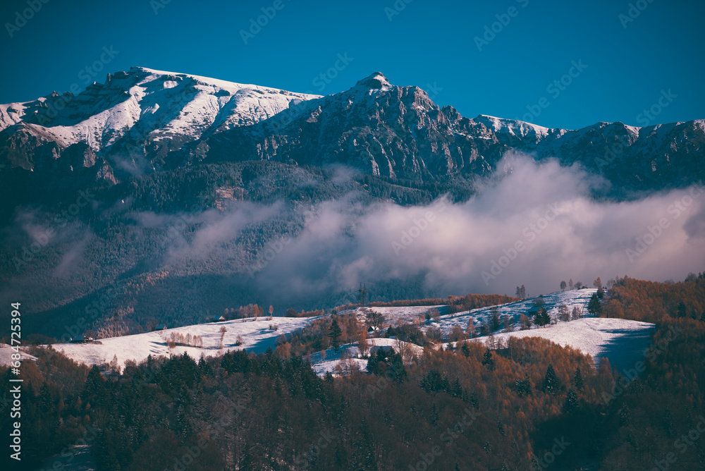 Winter landscape with snow-covered hills and mountains background. Human settlements in wild areas. Villages located in tourist areas - obrazy, fototapety, plakaty 