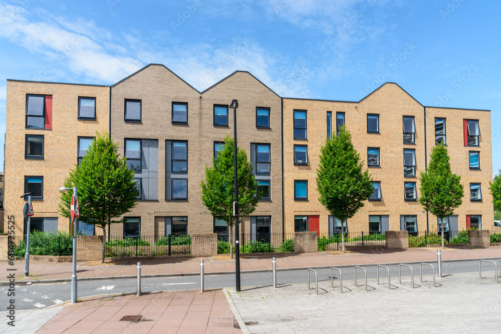 Exterior of a new block of flats along a tree lined street on a sunny summer day